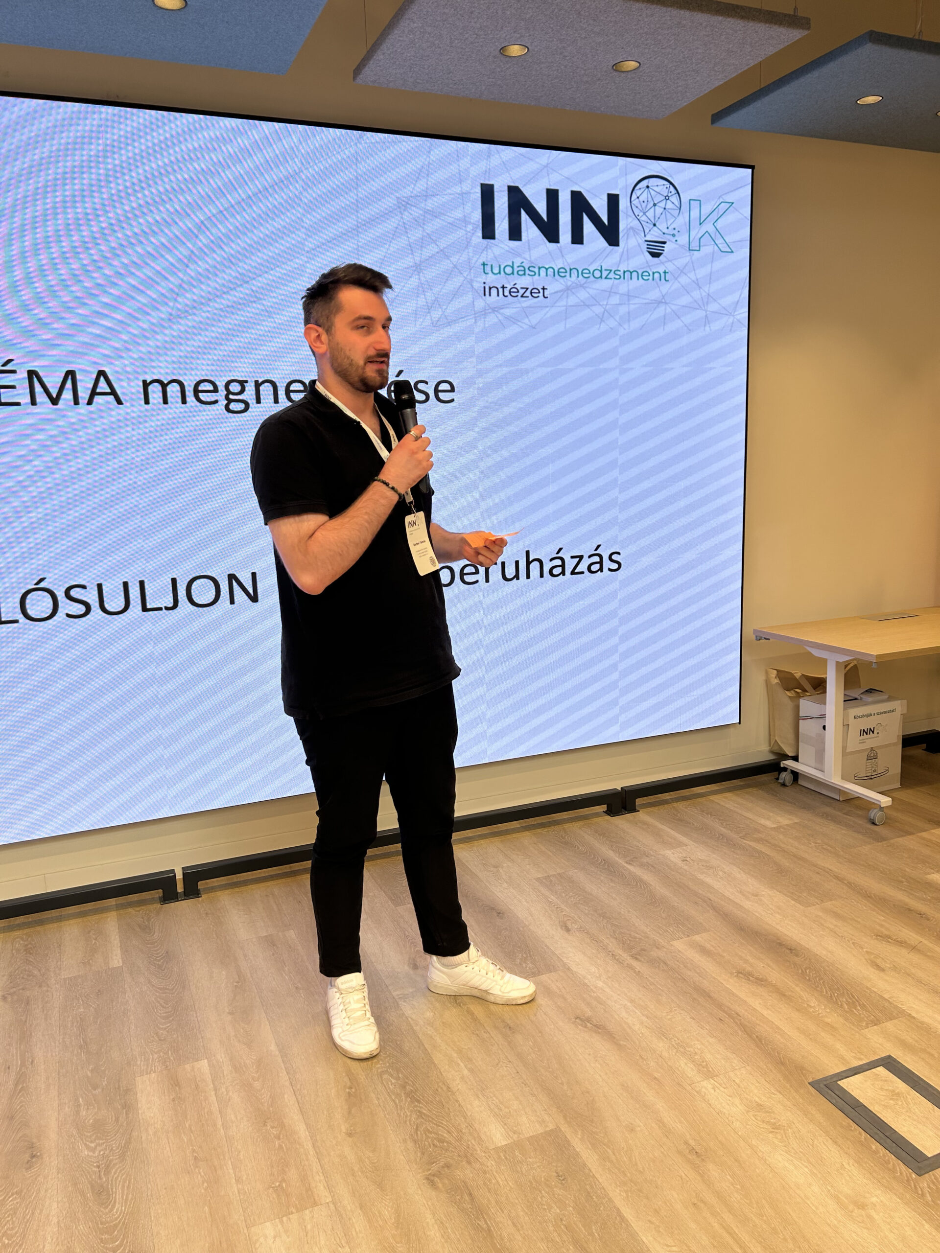 Facilitátor a záró szavazás előtt, háttérben a szavazóurna